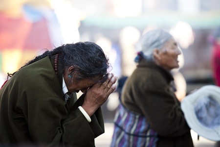 Jokhang Temple, Tibet, China - 07 October, 2011: A senior man is praying in front of the Jokhang Temple, a senior woman in the background.のeditorial素材