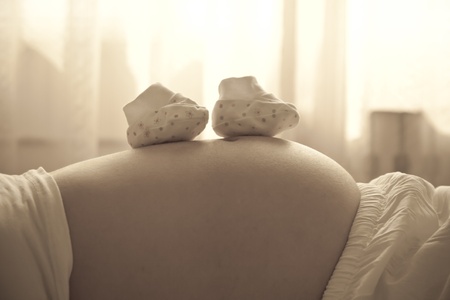 Pregnant woman with small baby shoesの写真素材