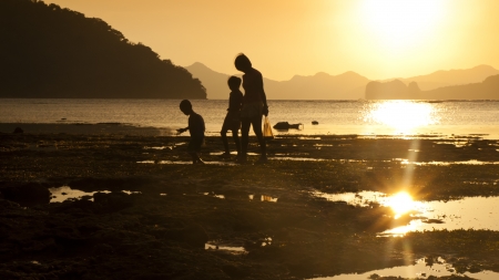 Mother and children silhouette at sea sunset, they are walking along the beach の写真素材