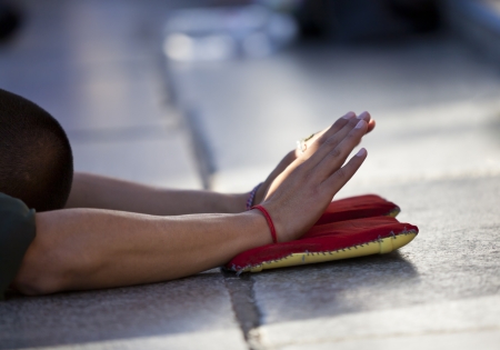 A Tibetan pilgrim praying in front of the Jokhang Temple in Lhasa, Tibetの写真素材