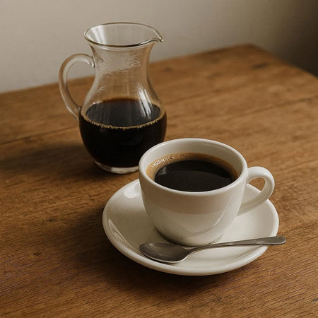 Coffee in a cup and a jug on a wooden table