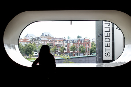 Silhouette of a woman watching outside the window of Stedelijk Museum in Amsterdam, Netherlands.のeditorial素材
