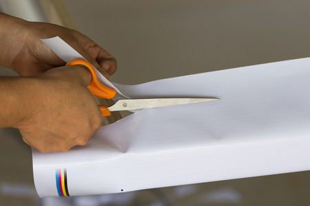 Women hand is cutting vinyl fabric  with scissors.の写真素材