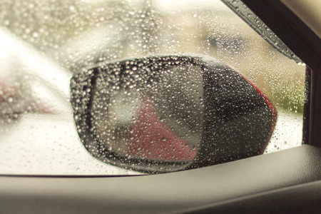 Raindrops on the car rearview mirror. Heavy rain outside