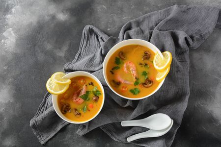 Tom Yam - traditional spicy Thai soup with shrimps,coconut milk, chilli pepper, lemon, mushrooms. Asian soup. White bowls on dark background.の写真素材