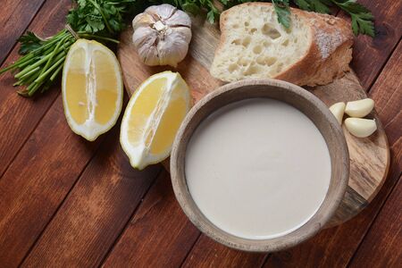 Tahini sauce made from sesame seeds in bowl with parsley on wooden backgroundの写真素材
