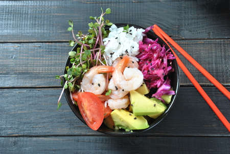 Organic food. Fresh seafood recipe.poke bowl with  shrimps, rice, red cabbage, avocado, cherry tomatoes and radish sprouts on wooden background. Food concept Poke Bowlの写真素材