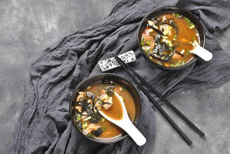 Japanese miso soup with fresh tuna, dried seaweed, tofu, shiitake dried mushrooms in a wooden bowl on the wooden backgroundの写真素材