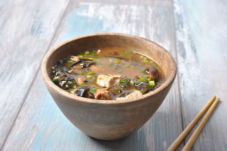 Japanese miso soup with fresh tuna, dried seaweed, tofu, shiitake dried mushrooms in a wooden bowl on the wooden backgroundの写真素材