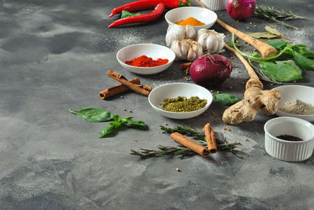 Colorful various of fresh and dried herbs, spices for cooking. Spice and herb seasoning, paprika powder, cinnamon, red onion. garlic, basil, ginger root on dark background.の写真素材