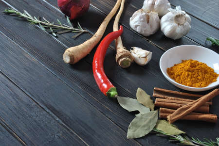 Colorful various of fresh and dried herbs, spices for cooking. Spice and herb seasoning, paprika powder, cinnamon, red onion. garlic, basil, ginger root on dark background.の写真素材