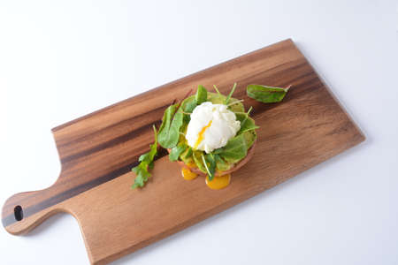 Poached egg with avocado, arugula beet leaves, black pepper on toast. Healthy breakfast conceptの写真素材