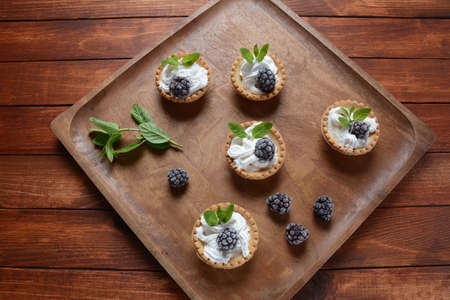 Homemade tartlets with blackberry, whipped cream and mint. Tasty sweet dessert conceptの写真素材