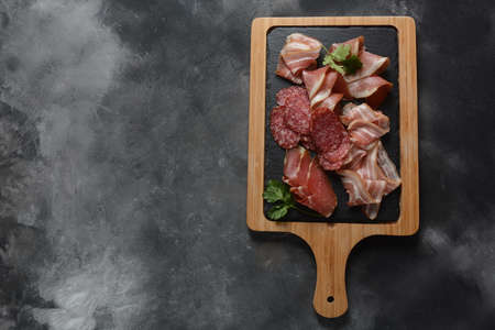 Salami, prosciutto, bacon on the cutting board. Delicatessen assortment of cold meat