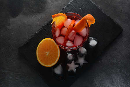 Negroni cocktail. Smoky Italian aperitivo with gin, campari, martini rosso, orange and ice cubes served in glass on dark stone backgroundの写真素材