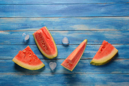 Fresh watermelon slices with ice cubes on a blue wooden rustic backgroundの写真素材