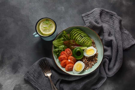 Vegan Buddha bowl with buckwheat, avocado, boiled eggs, cucumber, arugula beet leaves. Diet, detox,...