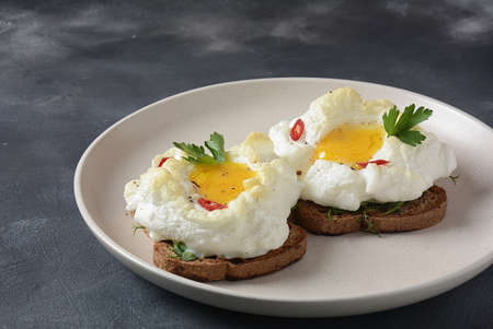 Delicate baked egg. Orsini eggs in the cloud. French breakfast.Cloud egg on toast
