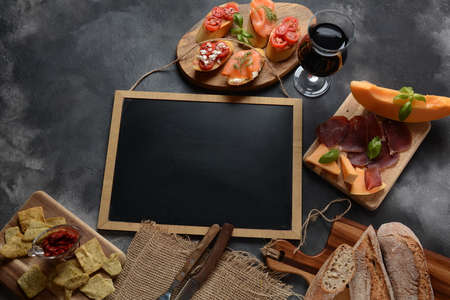 Brushetta or traditional Spanish tapas. Appetizers with Italian antipasti snacks. Variety of small sandwiches with  cherry tomatoes, salmon, cream cheese.  Prosciutto  served with melon and basilの写真素材