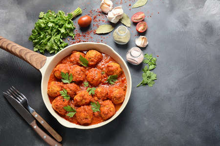 Meatballs in sweet and sour tomato sauce with spices served in a frying pan on dark background . Top viewの写真素材