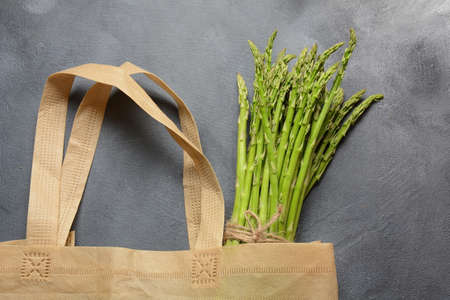 Reusable zero waste textile product bag filled with green asparagus and parsley