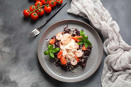 Squid Ink Pasta with seafood, parmesan, basil leaves, cherry tomatoes. Black spaghetti, black organic noodles with shrimps. Mediterranean gourmet food.の写真素材