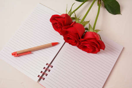 Notebook, pen and rose flowers.の写真素材