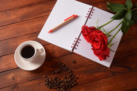 Cup of coffee, notebook, pen and rose flowers. Morning coffee breakの写真素材