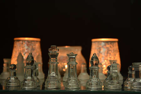 Clear glass chess pieces on a glass chessboard isolated on a black backgroundの写真素材