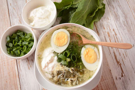 Green sorrel and spinach soup with boiled egg, spring onion and sour cream on white wooden rustic table. Diet or healthy food conceptの写真素材