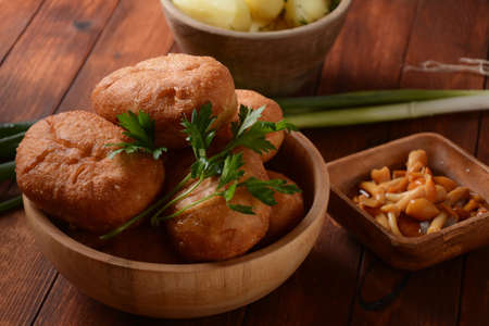Stuffed Buns (Pirozhki) in wooden bowl on the wooden background. With green onions and Homemade...