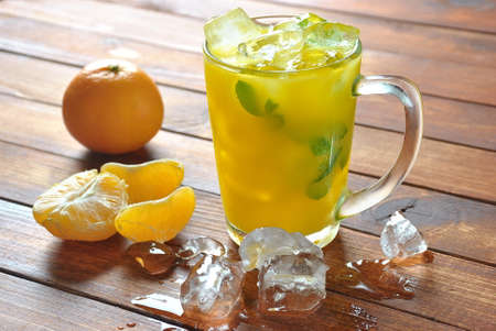 Orange juice with ice and mandarin on wooden baseの写真素材