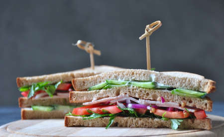 Fresh sandwich with ham, tomatoes, lettuce, onion on black backgroundの写真素材