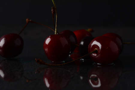 Cherries, with drops of water on a black background with reflectionの写真素材