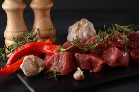 Raw chopped (diced)meat with spices, chili pepper rosemary. On black backgroundの写真素材