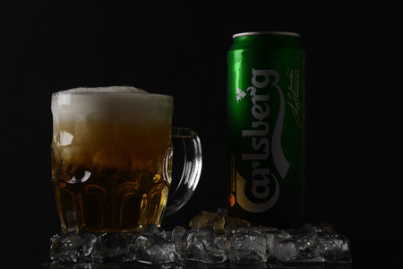 NETANYA,ISRAEL- June 29, 2020: Cold glass and aluminum can of Carlsberg beer black background. Danish brewing company founded in 1847.のeditorial素材