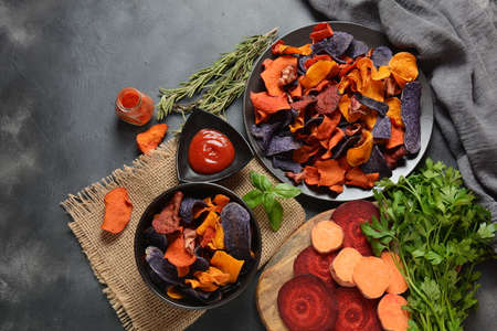 Baked vegetable chips- garnet sweet potato, purple sweet potato, carrot and beetroot. Gluten-free, dairy-free and vegan. Healthy food conceptの写真素材