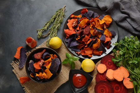 Baked vegetable chips- garnet sweet potato, purple sweet potato, carrot and beetroot. Gluten-free, dairy-free and vegan. Healthy food conceptの写真素材