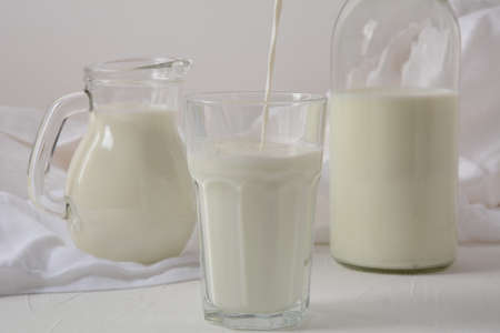Milk in a glass, jar, and bottle, on white backgroundの写真素材