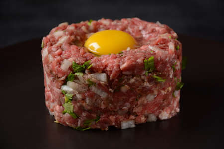 Beef tartare with raw egg,  and onions, fresh herbs. French cuisine