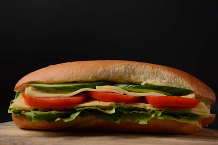 Sandwiches with cheese, lettuce, tomatoes and onion on a on a dark backgroundの写真素材