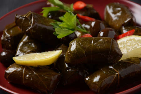 Traditional Greek cuisine. Wrapped rice in grape leaves. Dolma with lemon, spices, various pickled olives and hot peppers.の写真素材