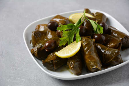Traditional Greek cuisine. Wrapped rice in grape leaves. Dolma with lemon, spices, various pickled olives and hot peppers.の写真素材