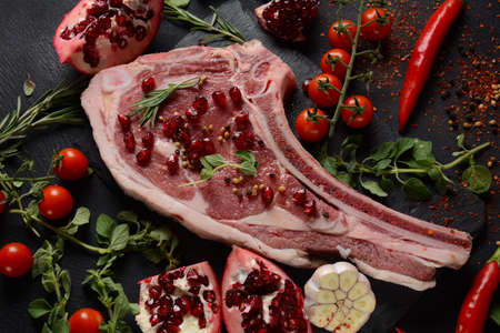 Fresh Raw Beef bone rib steak on black board with herbs and spicesの写真素材