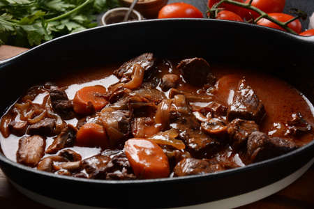 Beef Bourguignon in a pan. Stew with red wine ,carrots, onions, garlic, a bouquet garni, and garnished with pearl onions, mushrooms and bacon. French cuisine- regional recipe from Burgundyの写真素材