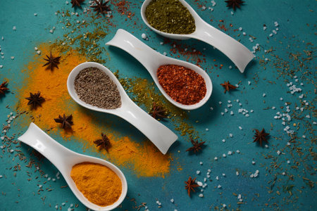 Various colorful herbs and spices for cooking in spoons. Pepper, chili, paprika, basil, turmeric.