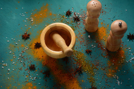 Wooden spice mortar and spices on blue background