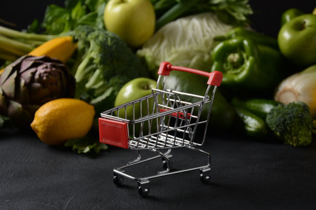 Shopping trolley cart and different fresh fruits and vegetables for layout. Assortment of fresh fruits and vegetables. Healthy food background. Shopping food in supermarketの写真素材