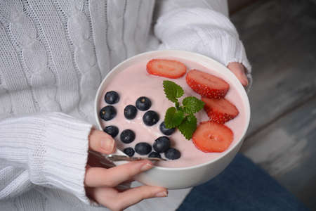 Bowl of fresh mixed berries and yogurt with farm fresh strawberries, and blueberries in girl's handsの写真素材