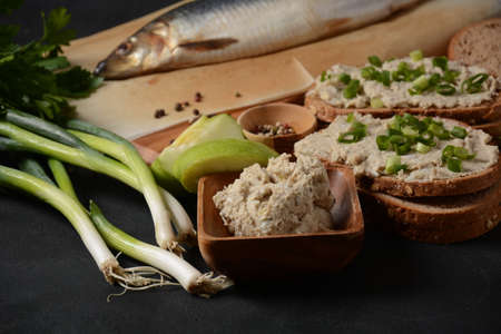 Traditional Jewish snack vorschmack or forshmak with bread and green onion, made of herring fillet and served with rye bread, dark stone backgroundの写真素材